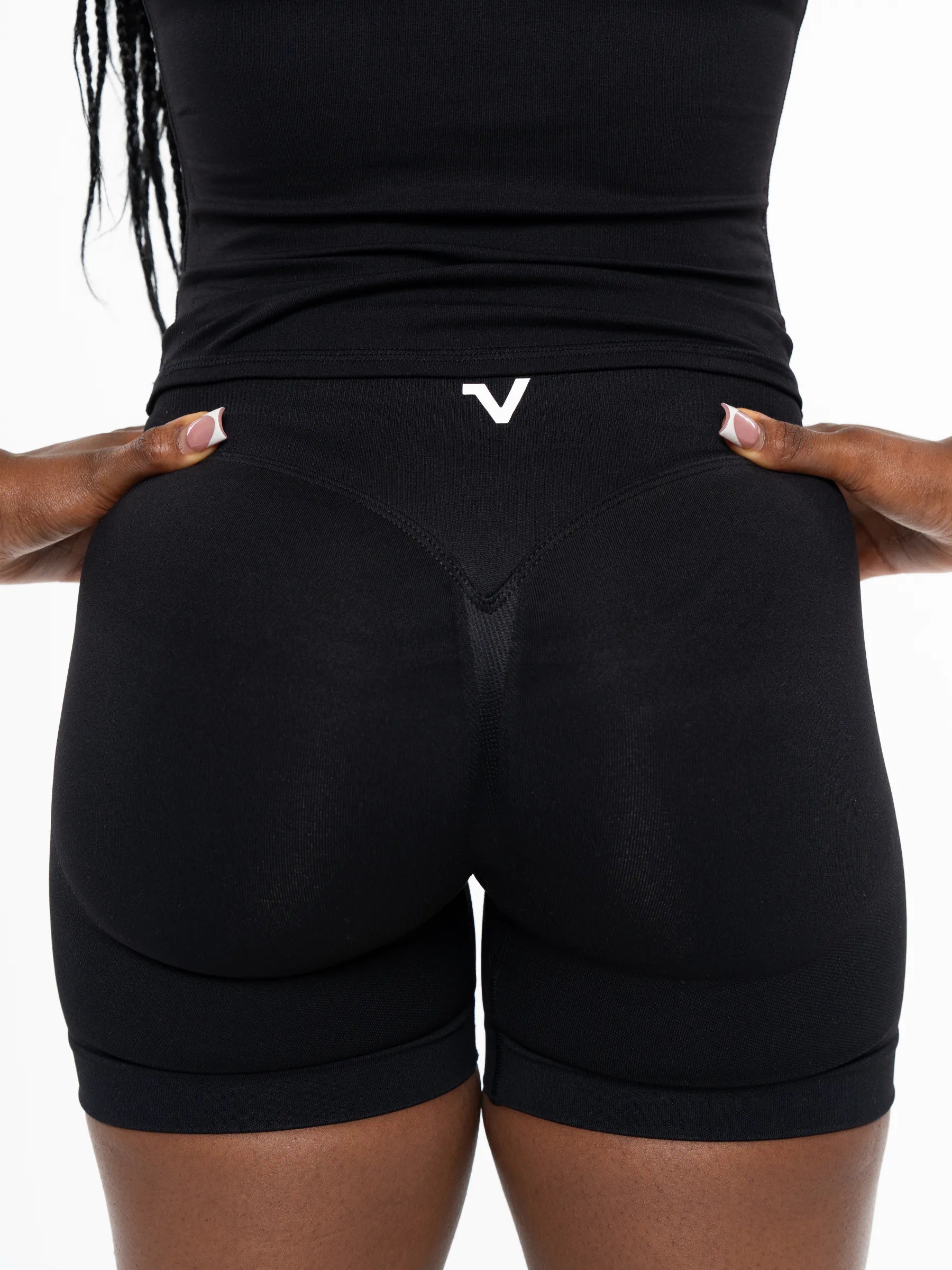Veritone Ease Shorts, Midnight Black – Rear view of a person wearing black compression-style athletic shorts with a small white stylized 'V' logo at the center back waistband, against a plain white background.