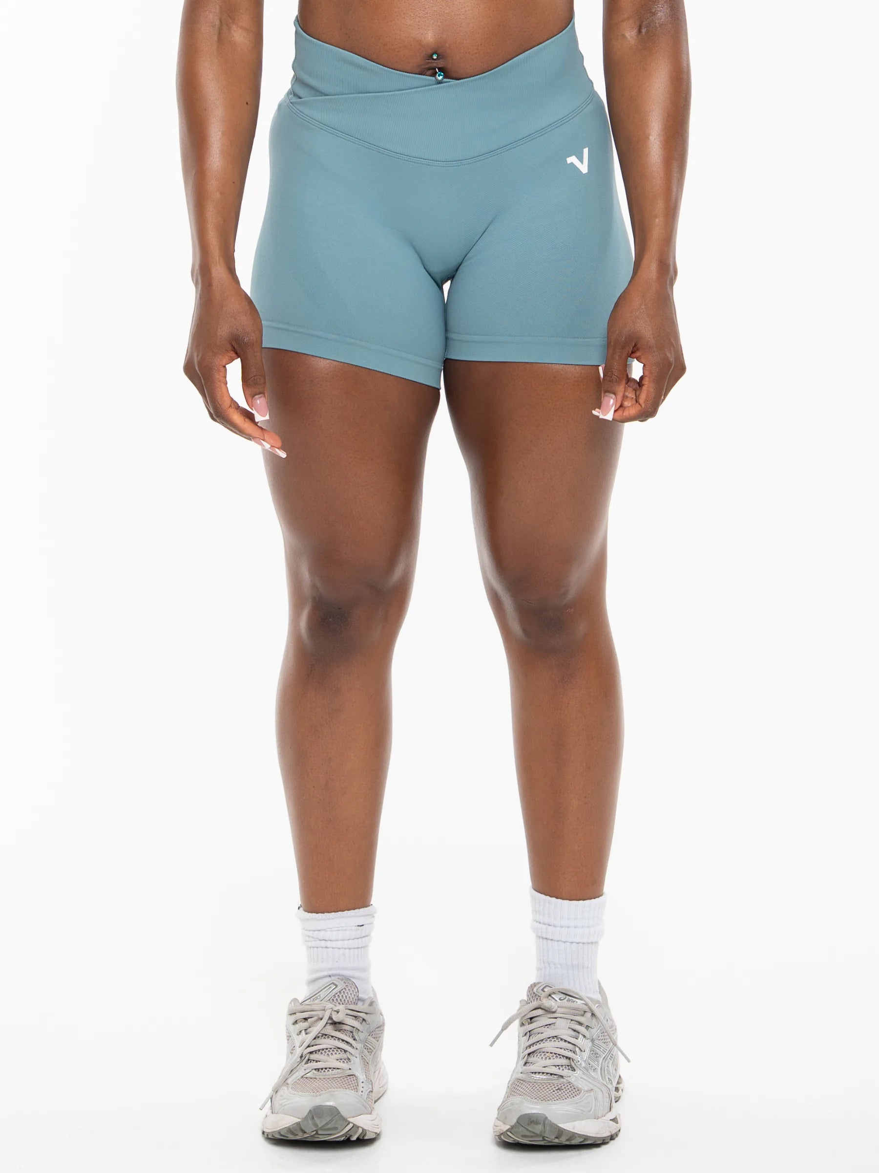 Veritone Ease Shorts, Ocean Mist – A model from the waist down wearing high-waisted, light blue athletic shorts with a small white logo on the left hip, paired with white socks and gray running shoes against a white studio background.