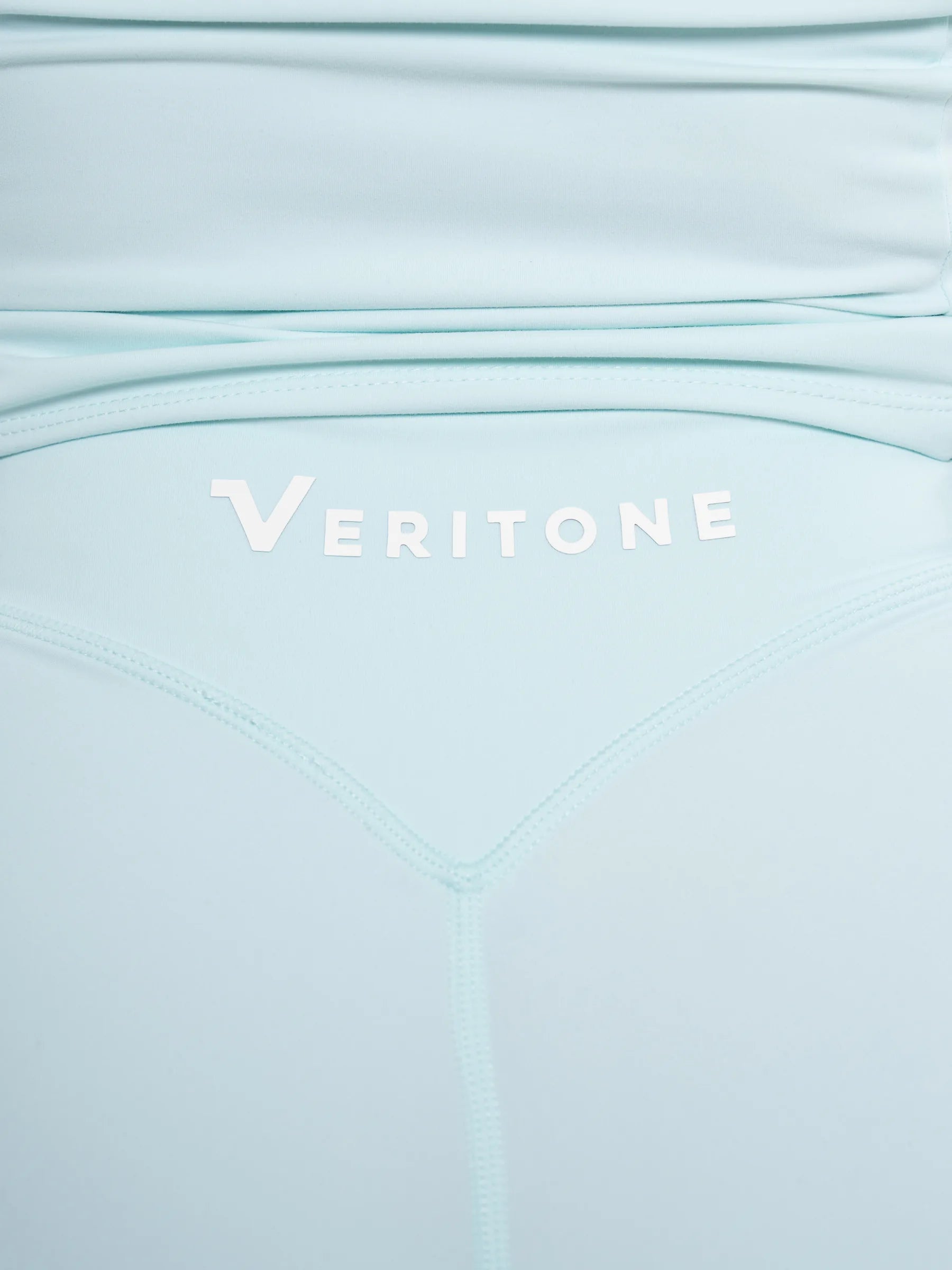 Veritone Élan Flared Pants, Ocean Mist – Close-up of a light blue athletic garment with the brand name 'VERITONE' printed in white across the waistband.