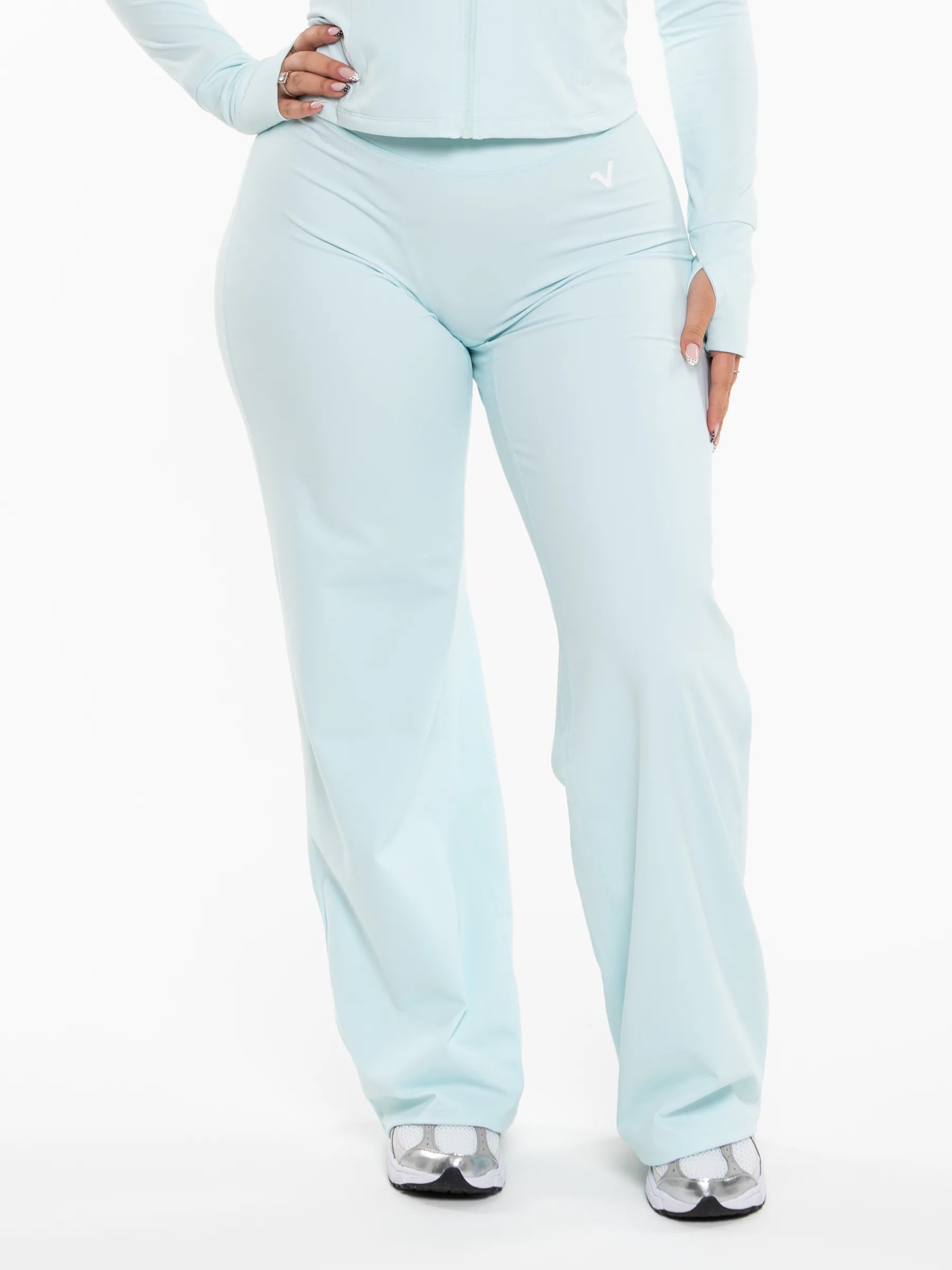 Veritone Élan Flared Pants, Ocean Mist – A person wearing light pastel blue wide-leg pants and a matching long-sleeve top, shown from the waist down against a plain white studio background.