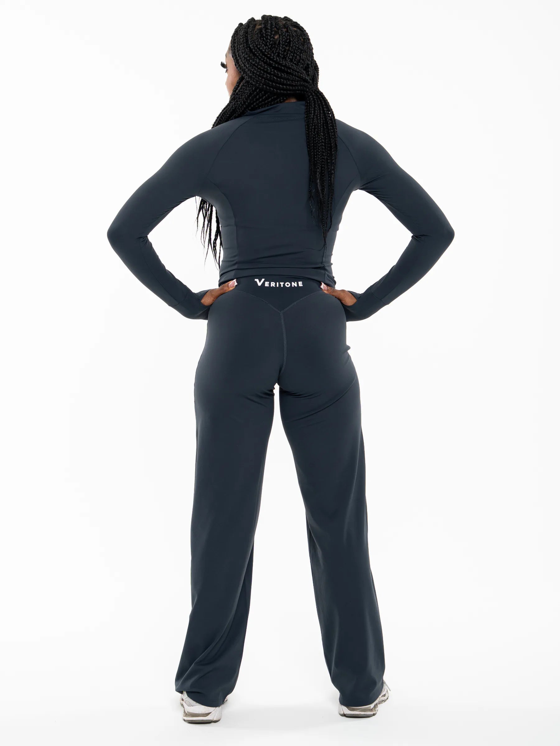 Veritone Élan Jacket, Storm Blue – A woman shown from the back wearing a dark navy long-sleeve athletic top and matching wide-leg sweatpants with a visible Ventrae logo at the waist, photographed against a clean white studio background.