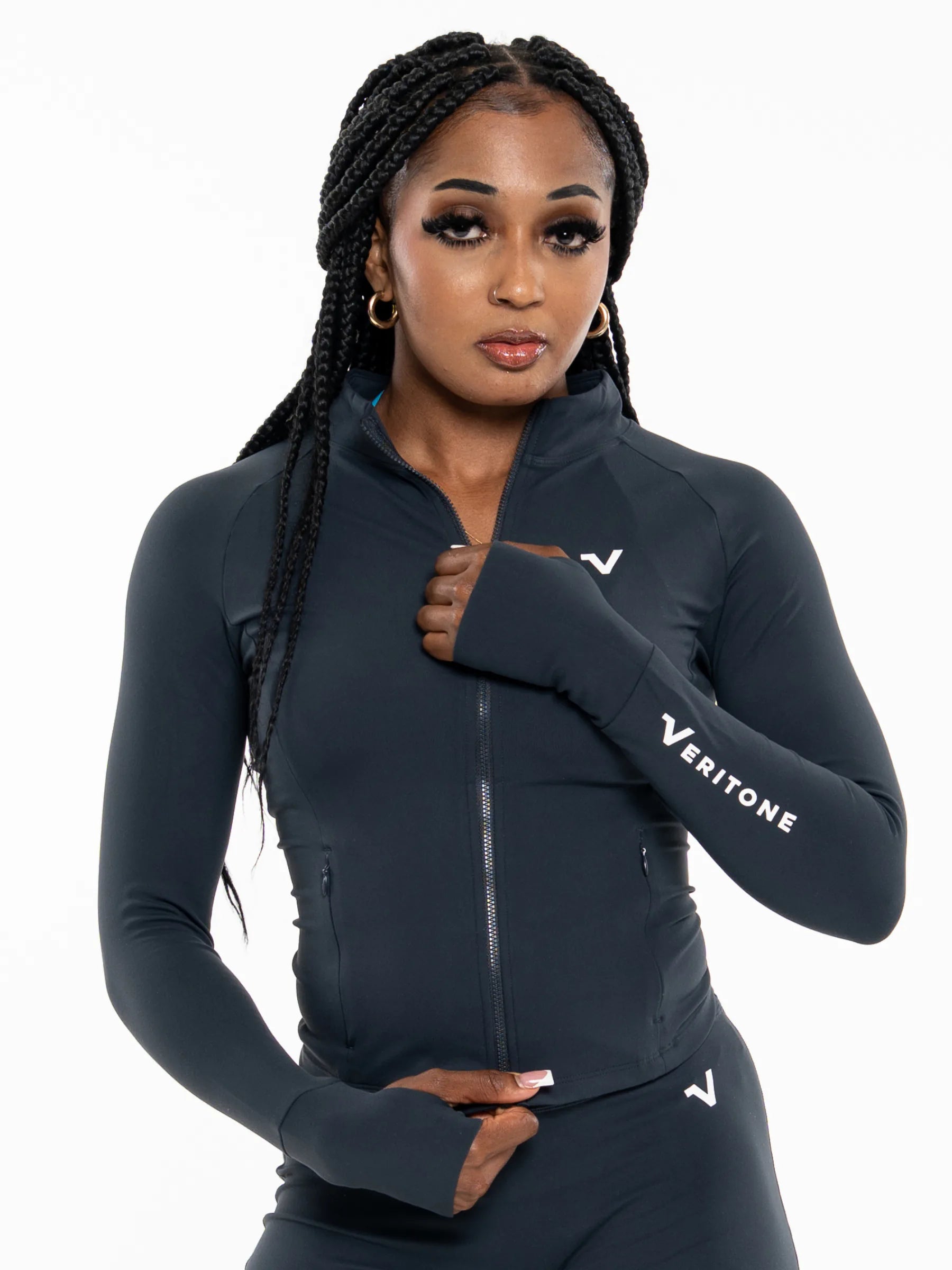 Veritone Élan Jacket, Storm Blue – A woman modeling a dark navy Veritone full-zip athletic jacket with matching arm warmers and leggings against a plain white background.