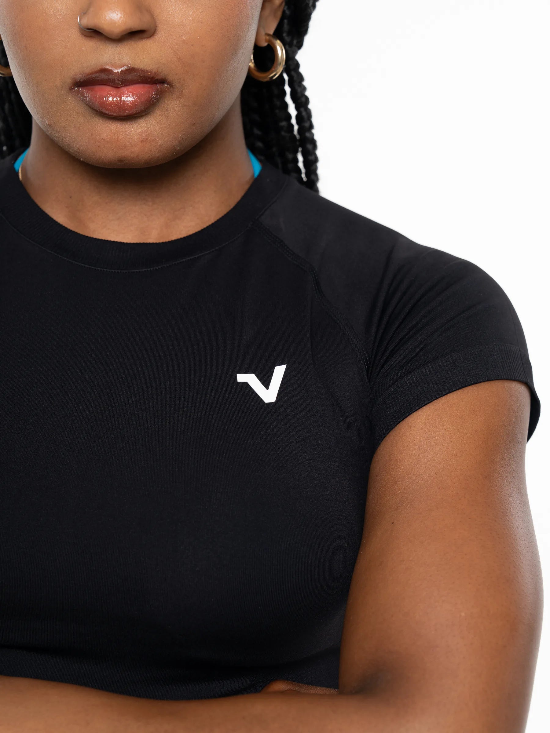 Veritone Form T-Shirt, Midnight Black – Close-up of a woman wearing a black short-sleeve athletic top with a small white stylized 'V' logo on the left chest, photographed against a light gray studio background.