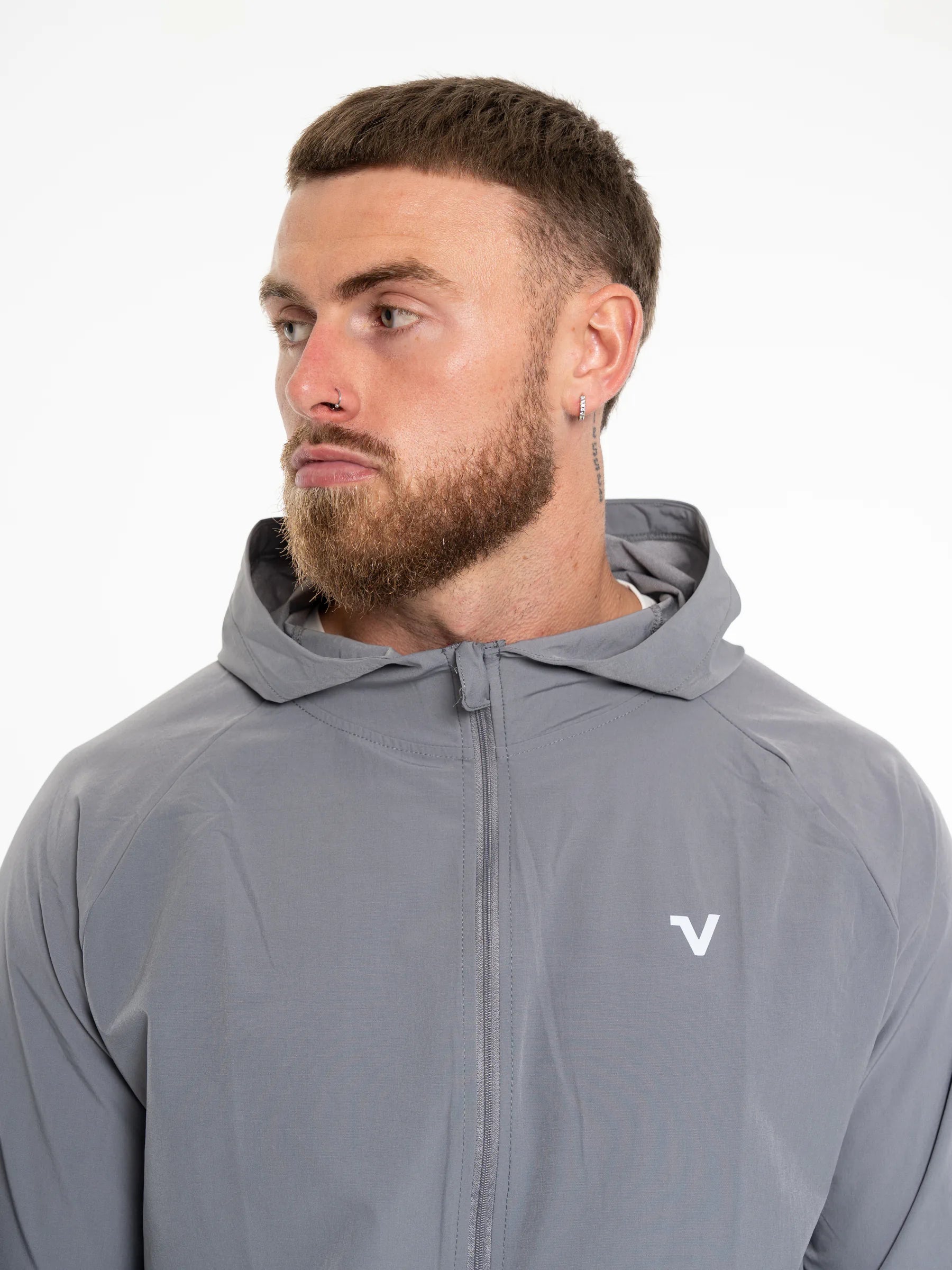 Veritone Mode Jacket, Ash Grey – A man wearing a gray full-zip hooded jacket with a small white stylized 'V' logo on the left chest, photographed against a plain white studio background.