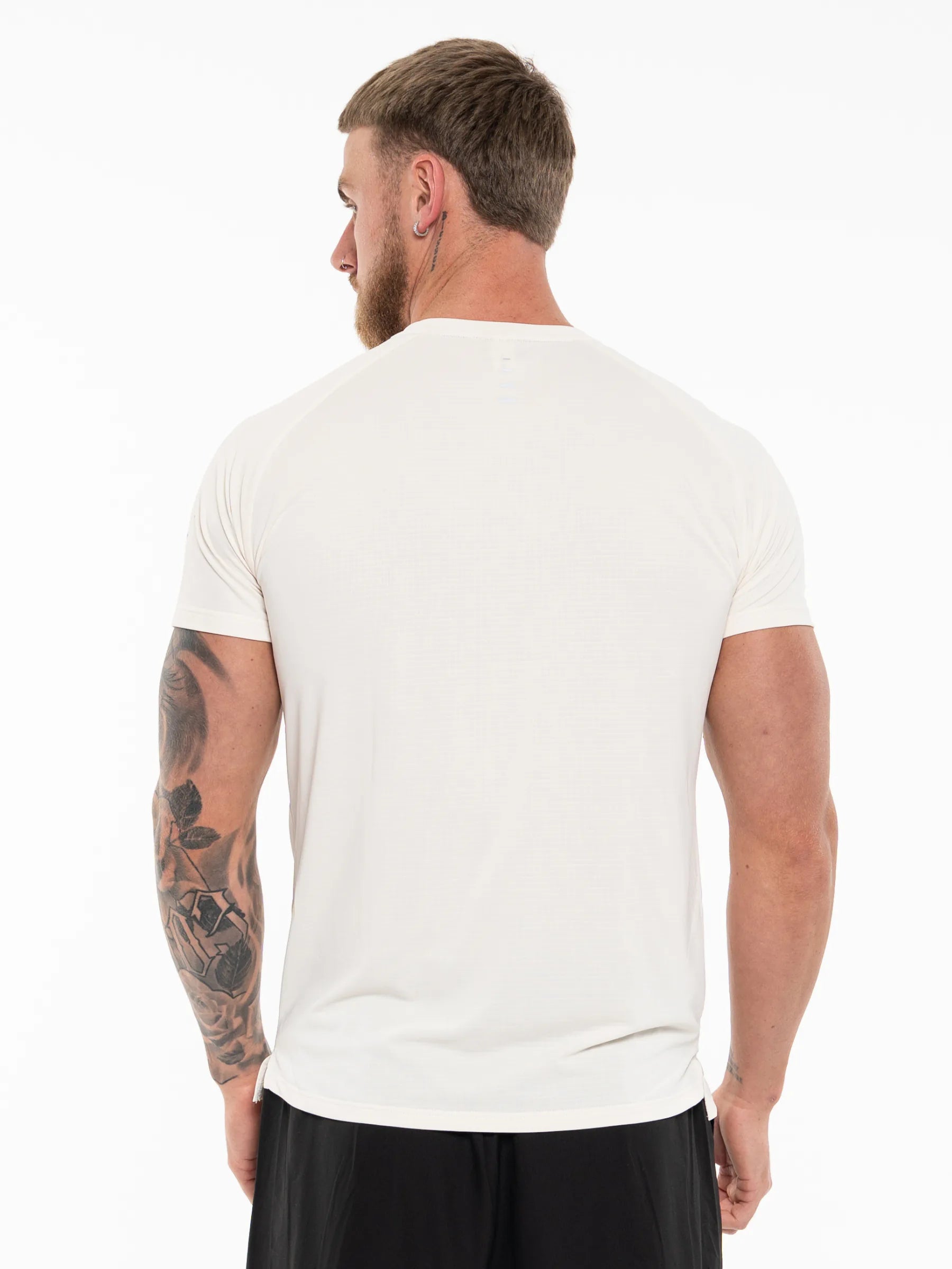 Veritone Prime Core T-Shirt, Cloud Cream – A man viewed from the back wearing a plain white short-sleeve crew-neck t-shirt and black shorts against a white studio background.