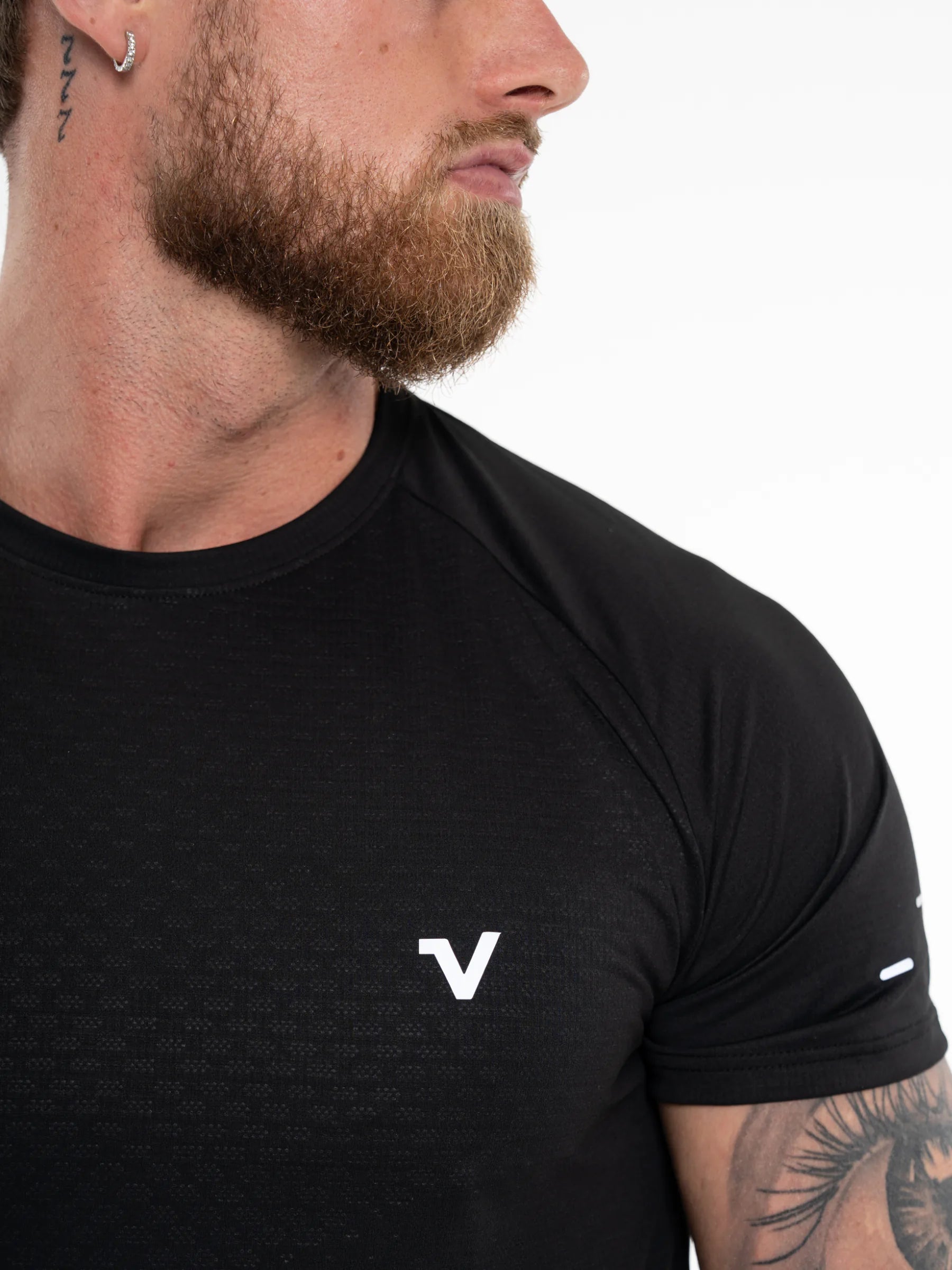 Veritone Prime Core T-Shirt, Midnight Black – Close-up of a man wearing a black athletic t-shirt with a white stylized 'V' logo on the chest, set against a plain white background.