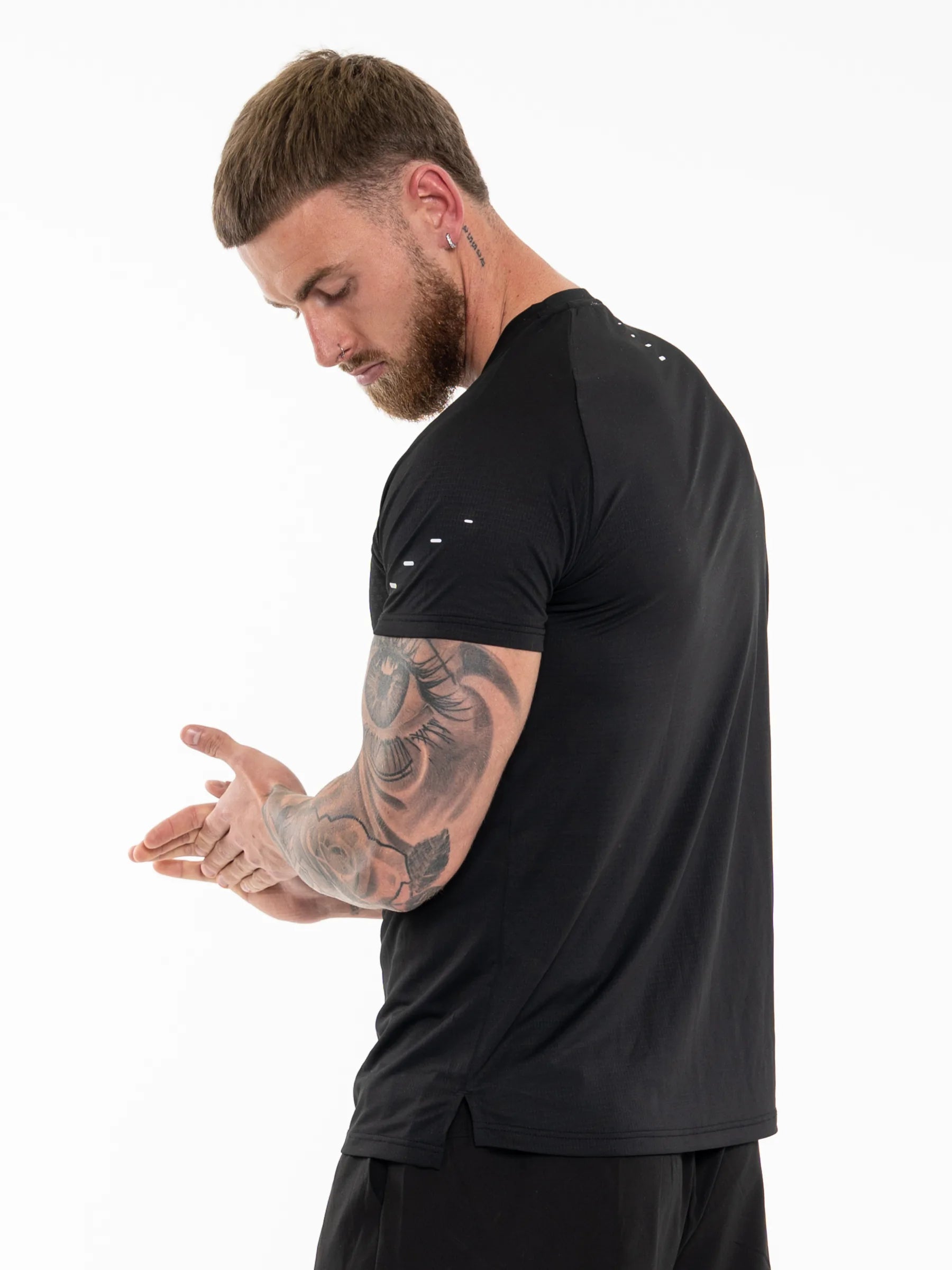 Veritone Prime Core T-Shirt, Midnight Black – A man with a beard and arm tattoos wearing a black athletic t-shirt, shown from a side-back angle against a plain white background.
