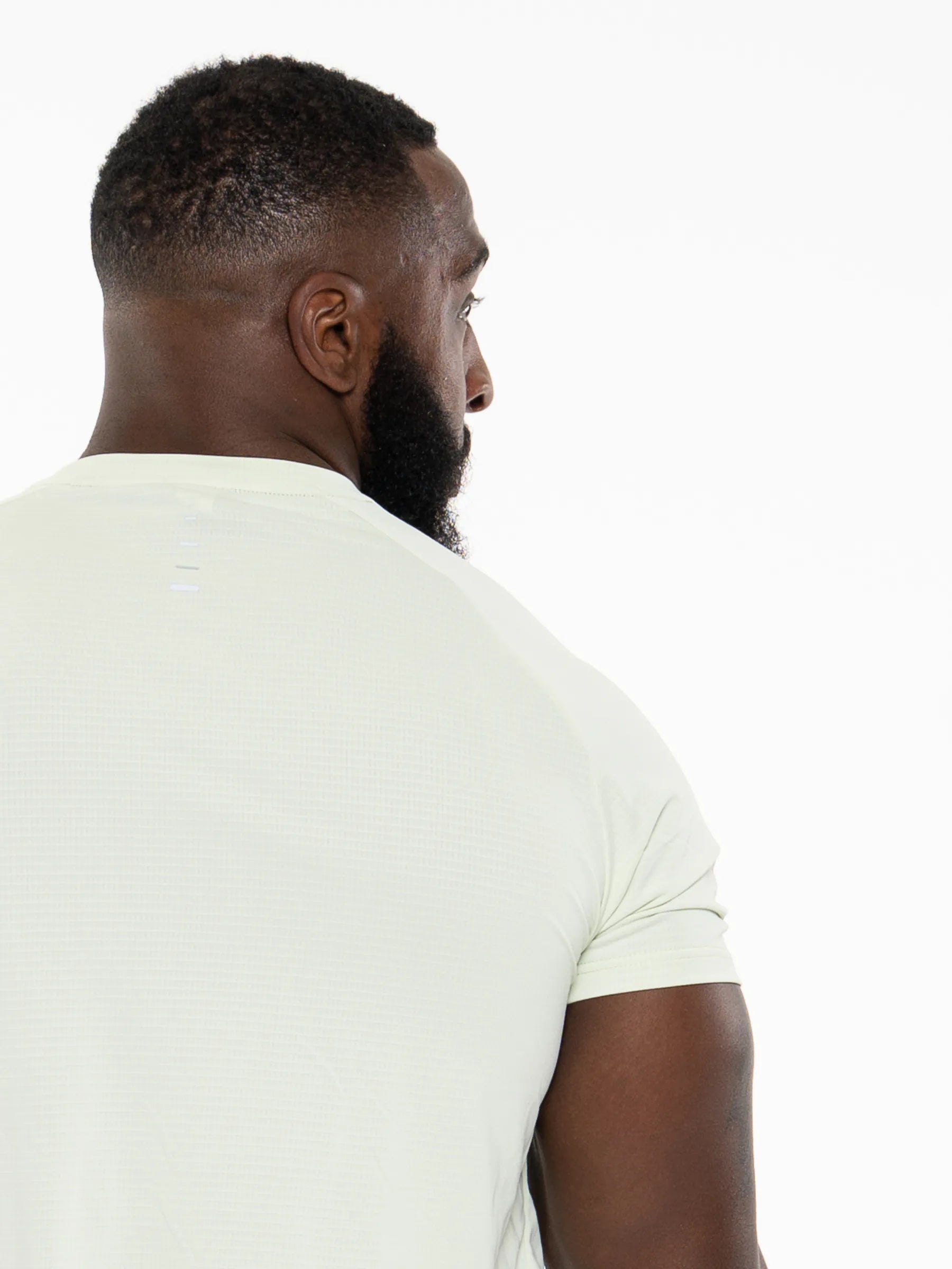 Veritone Prime Core T-Shirt, Volt Green – A man shown from the back wearing a light cream-colored short-sleeve athletic t-shirt against a solid white background.