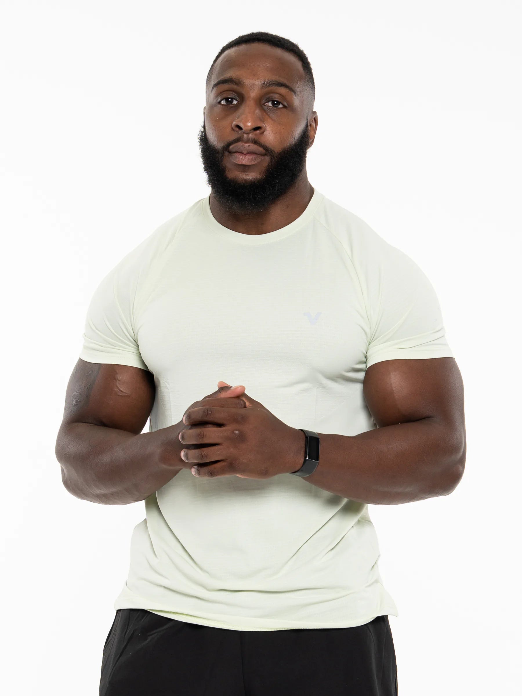 Veritone Prime Core T-Shirt, Volt Green – A muscular man with a beard wearing a pale yellow-green athletic t-shirt and black shorts, standing against a plain white background.