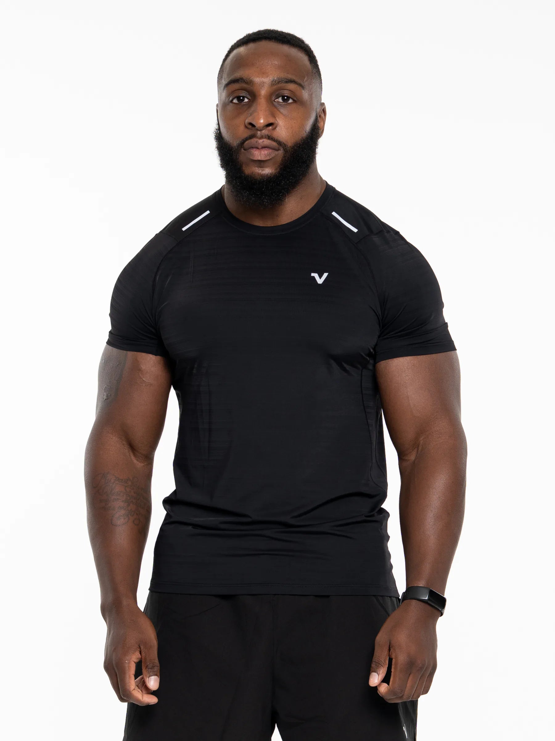 Veritone Prime Muscle Fit T-Shirt, Black – A muscular man wearing a black athletic short-sleeve t-shirt with a small white stylized 'V' logo on the left chest, photographed against a solid white studio background.