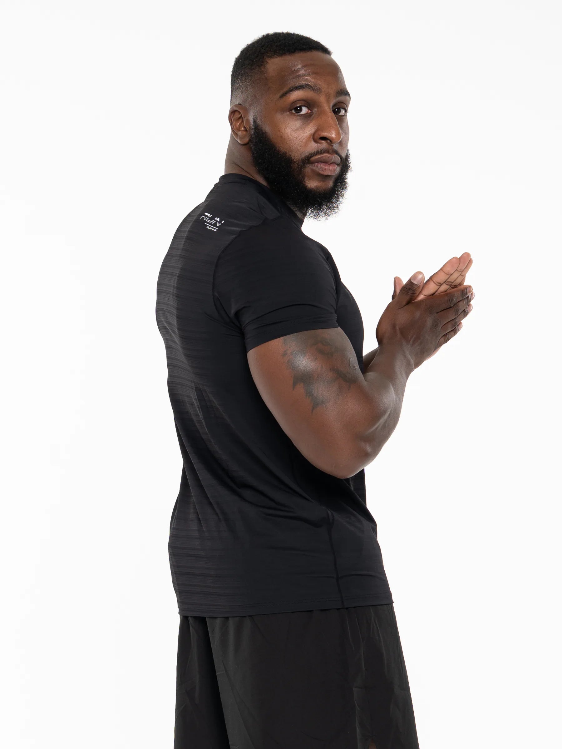 Veritone Prime Muscle Fit T-Shirt, Black - A man wearing a black athletic short-sleeve shirt and matching black shorts, shown from the back and side against a plain white studio background.