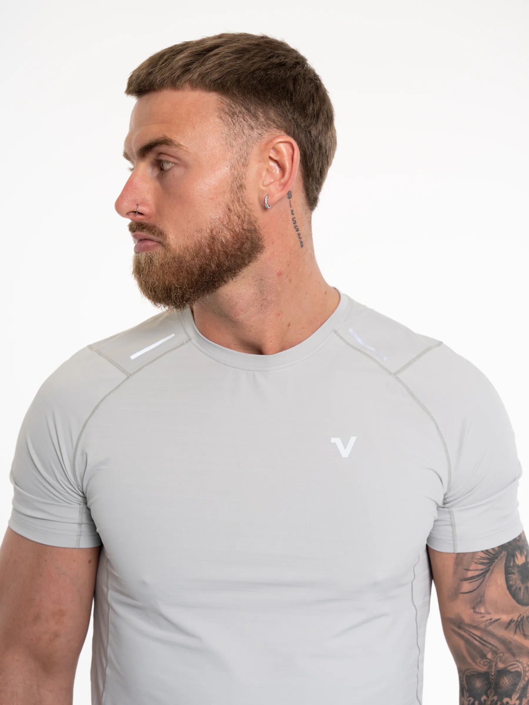 Veritone Prime Muscle Fit T-Shirt, Light Grey – A man wearing a light gray athletic short-sleeve compression shirt with a small white stylized 'V' logo on the left chest, shown in profile against a plain white background.
