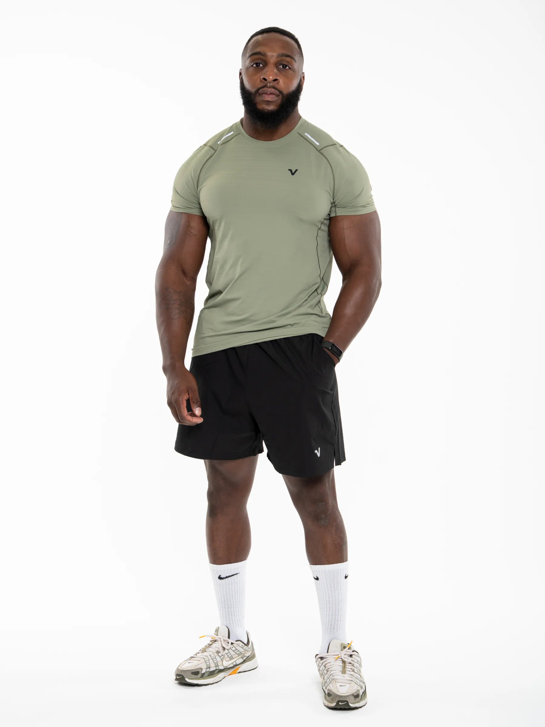 Veritone Prime Muscle Fit T-Shirt, Stone Khaki – Man wearing a green athletic shirt and black shorts on a white background.